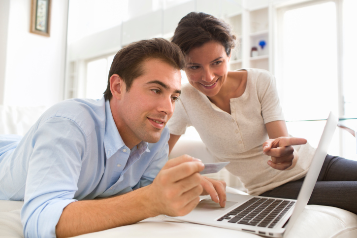 Couple using computer, holding a credit card